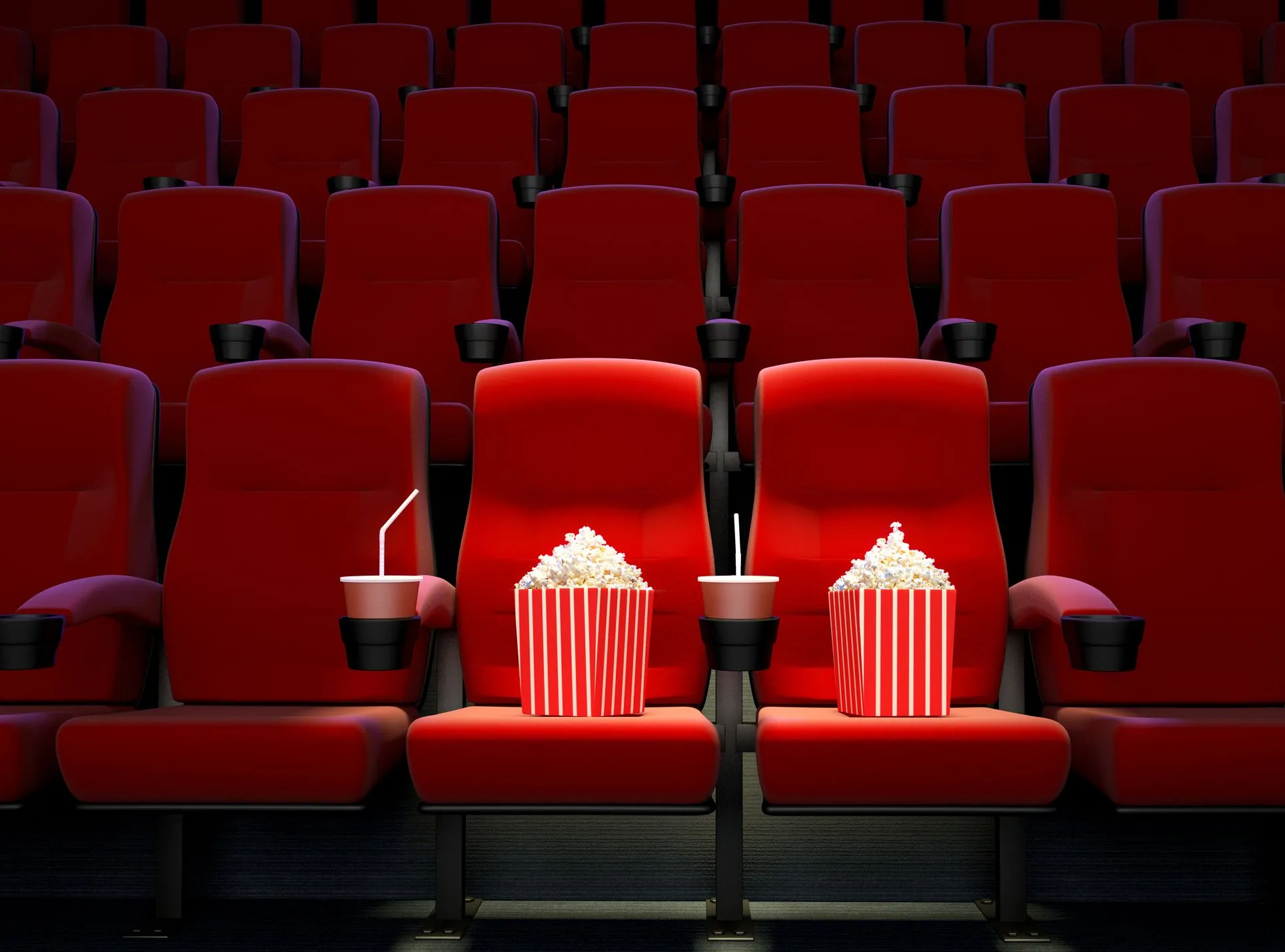 Cinema room with rows of red seats and cup holders