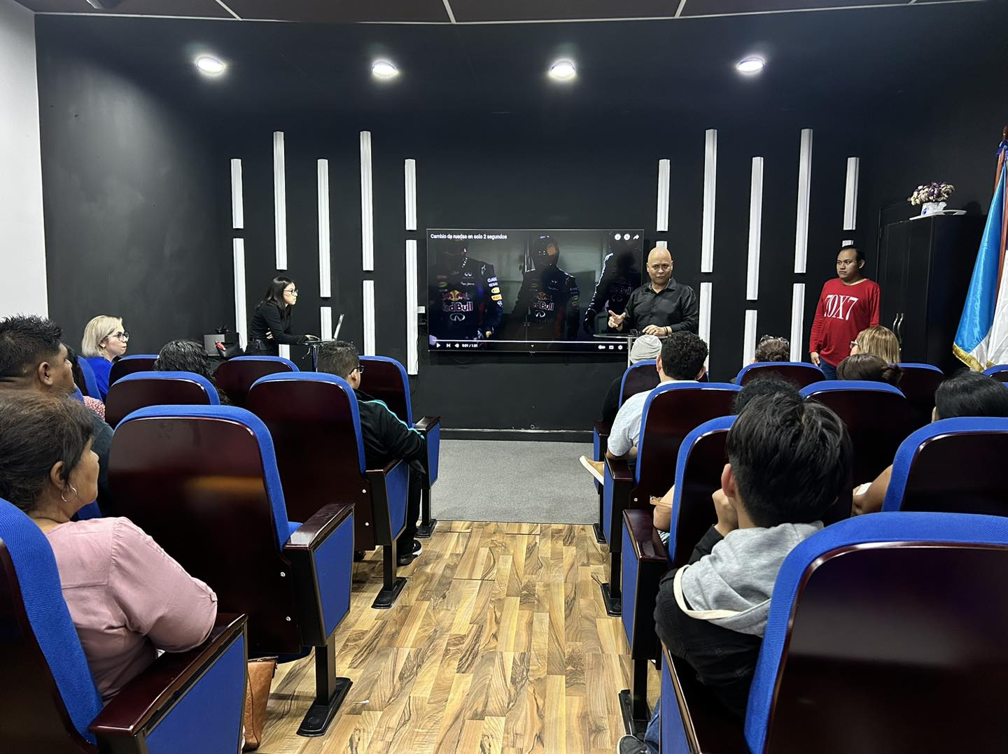 Compact auditorium with blue fixed seating during a presentation